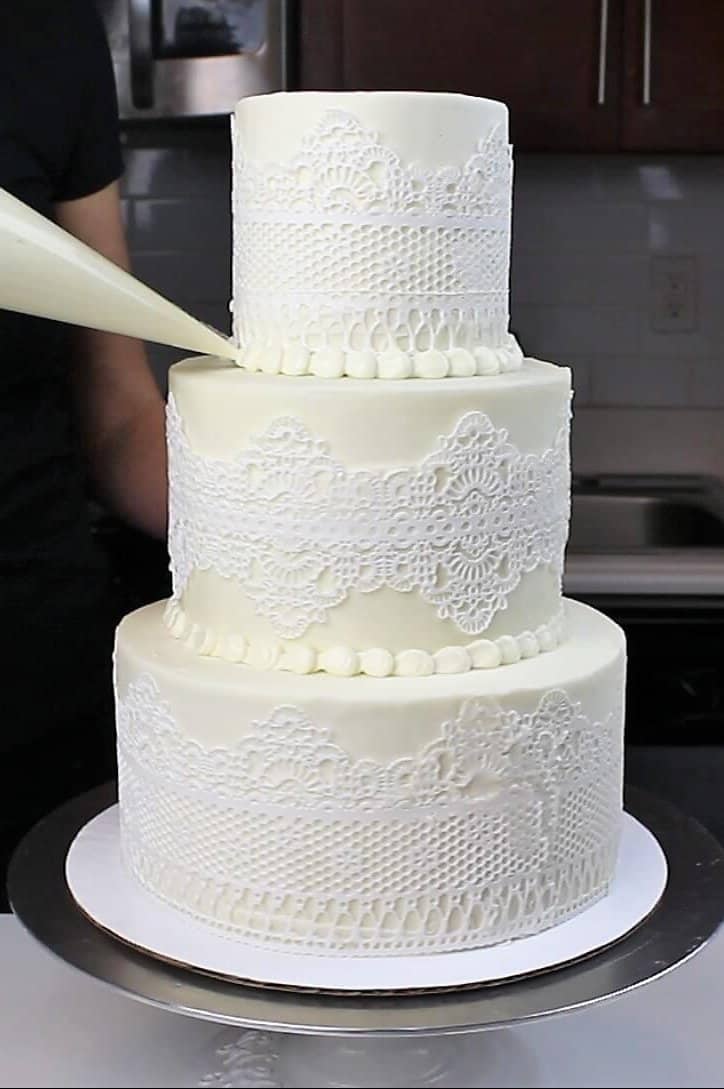 带有可食用花边的三层婚礼蛋糕图片