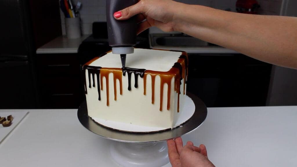 巧克力和焦糖滴被添加到士力架滴油蛋糕的图像