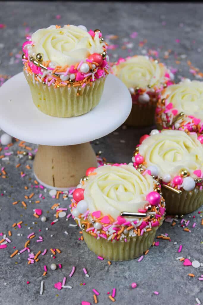 image of unwrapped vanilla cupcake decorated with a pretty sprinkle blend