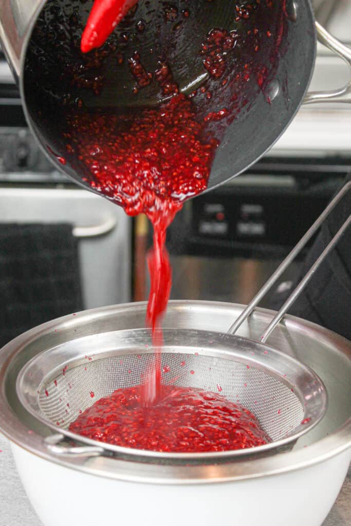 将覆盆子果酱倒入过滤器中，使其无籽用于蛋糕填充的图像