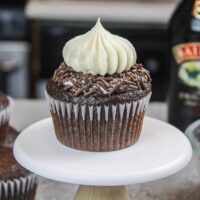 小蛋糕架上的贝利巧克力蛋糕的照片，装饰有巧克力洒