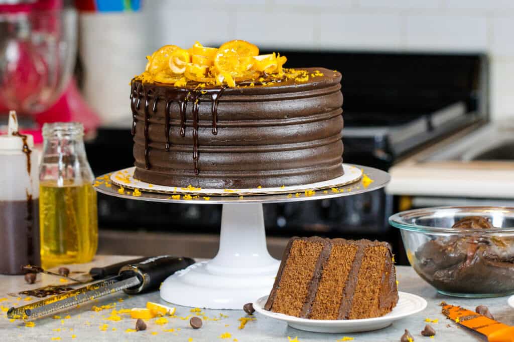 巧克力橙色蛋糕的图片，在前面的盘子上的切片显示出蛋糕层是多么松软和柔软