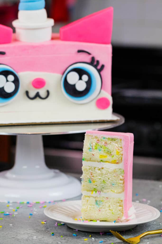 从unikitty蛋糕上切下一片funfetti蛋糕的图像