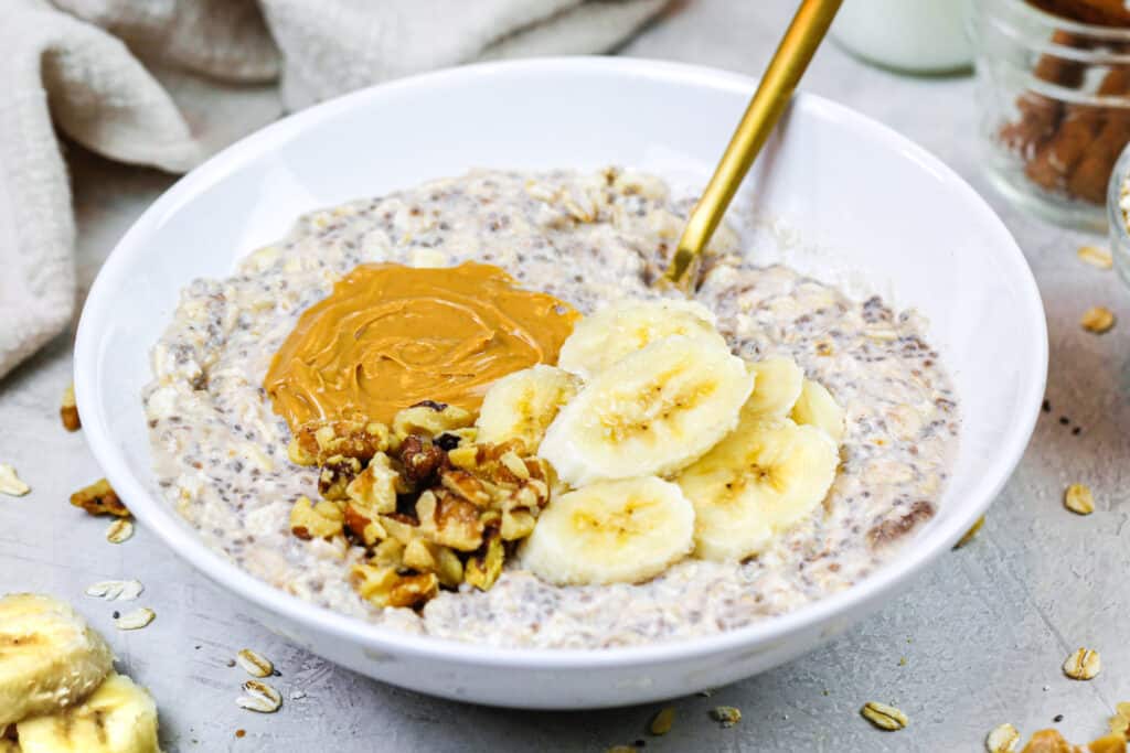 香蕉过夜燕麦的图象在碗上面用花生酱和切好的坚果颠倒