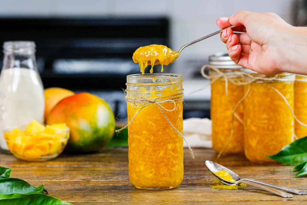 从玻璃瓶中舀出芒果果酱的画面