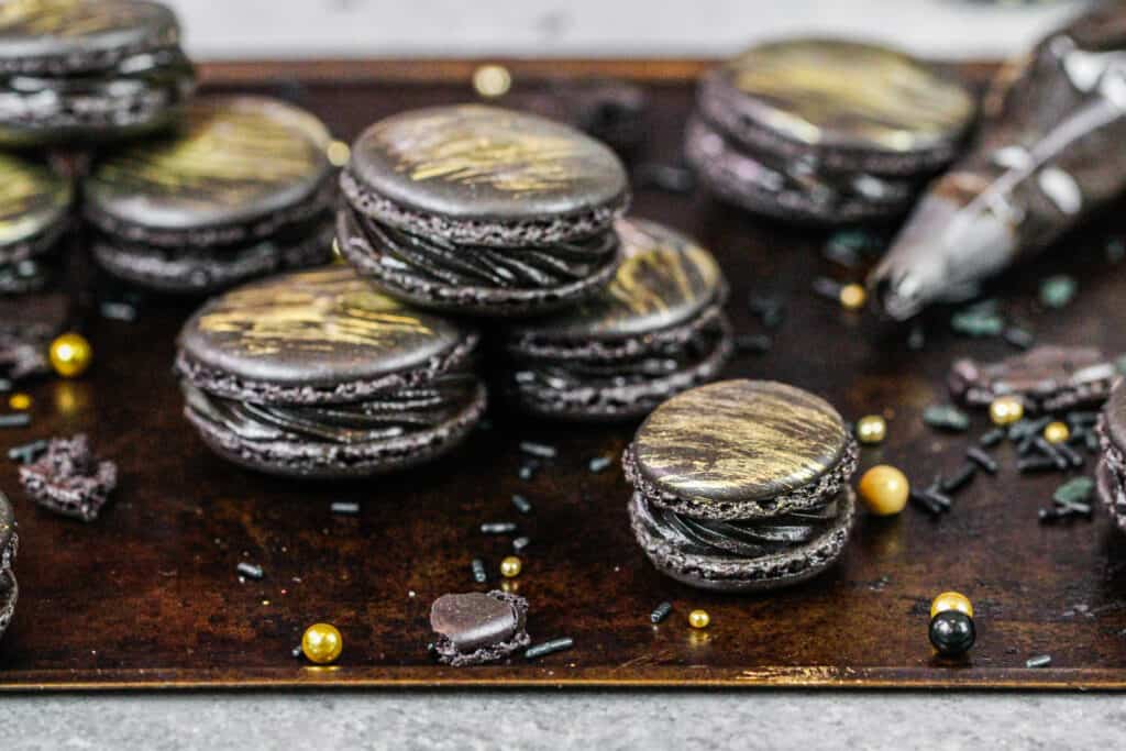 这是法国黑色马卡龙，里面涂满了黑色糖霜，刷上了一层漂亮的金色条纹可食用的金色涂料