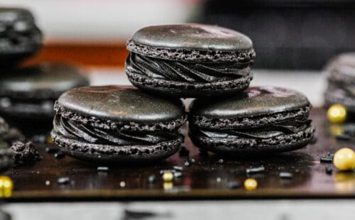 在烘烤盘子堆积的黑色macarons的图象显示他们的黑巧克力果子