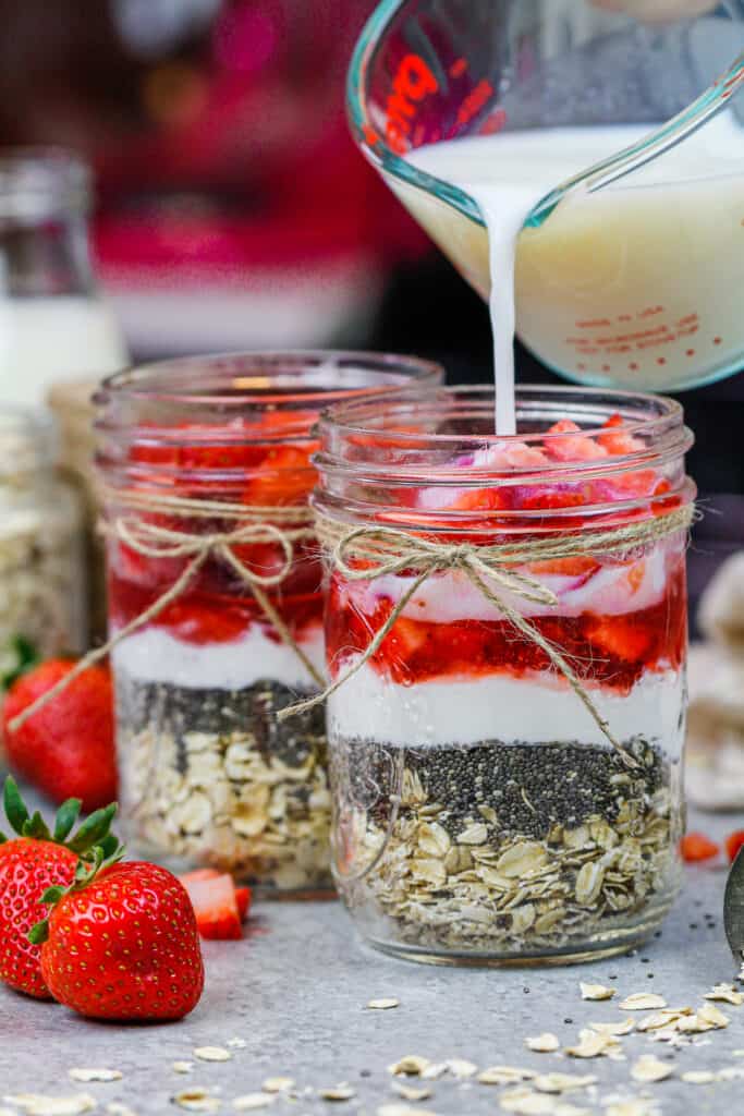 被涌入泥工瓶子的牛奶的图象充满成份，使草莓隔夜燕麦