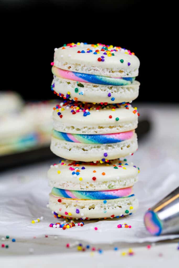 三个彩虹马卡龙堆叠在一起，炫耀他们的彩虹奶油