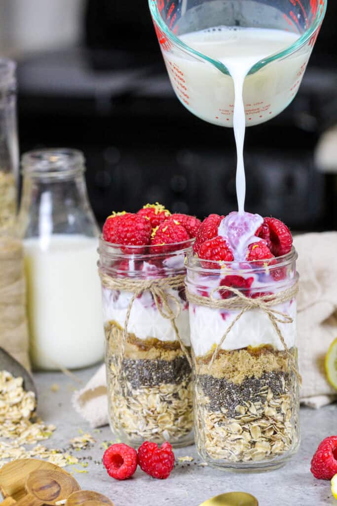 图像的牛奶被涌入mason jar覆盆子隔夜燕麦