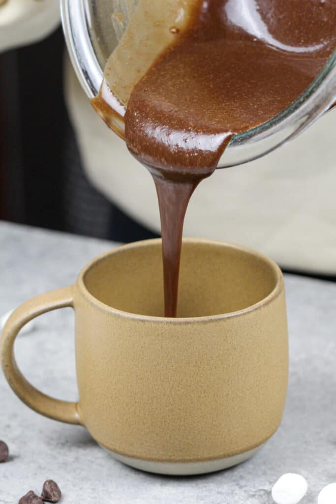 巧克力蛋糕糊被倒进一个杯子里，在微波炉里做一个蛋白质杯子蛋糕