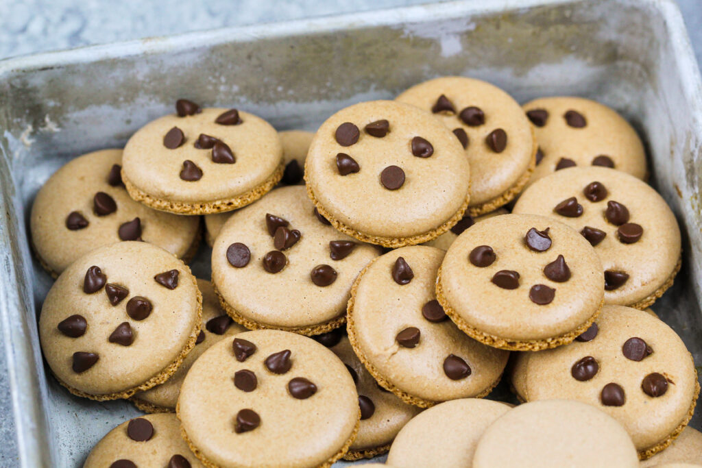 饼干面团马卡龙壳的图像，上面放着迷你巧克力片，使它们看起来像小饼干