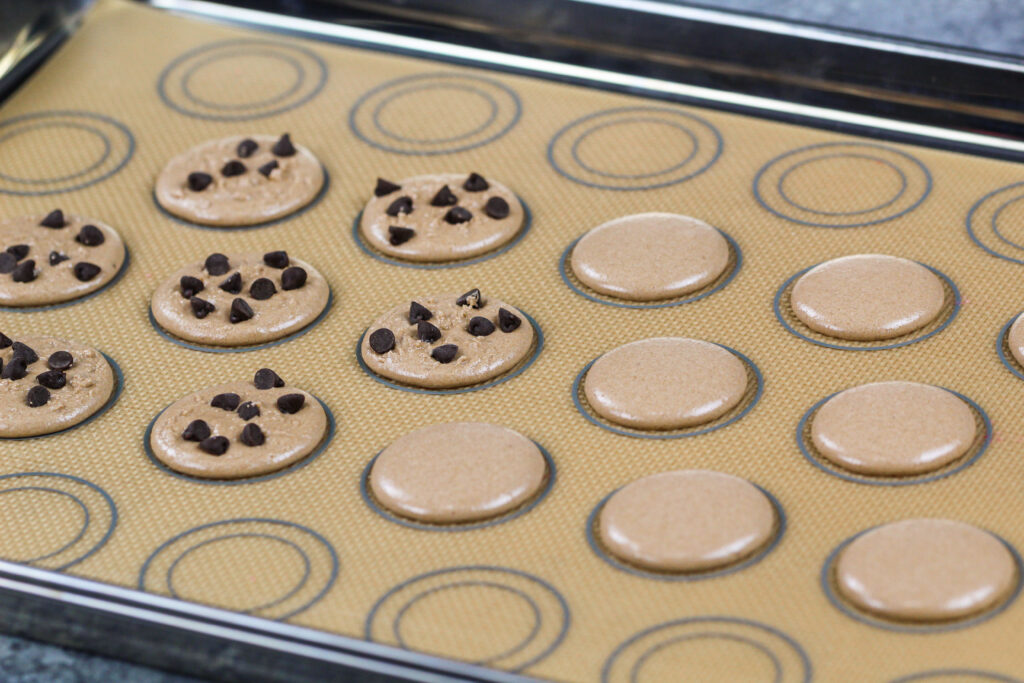 饼干面团马卡龙壳的图像，上面放着迷你巧克力片，使它们看起来像小饼干