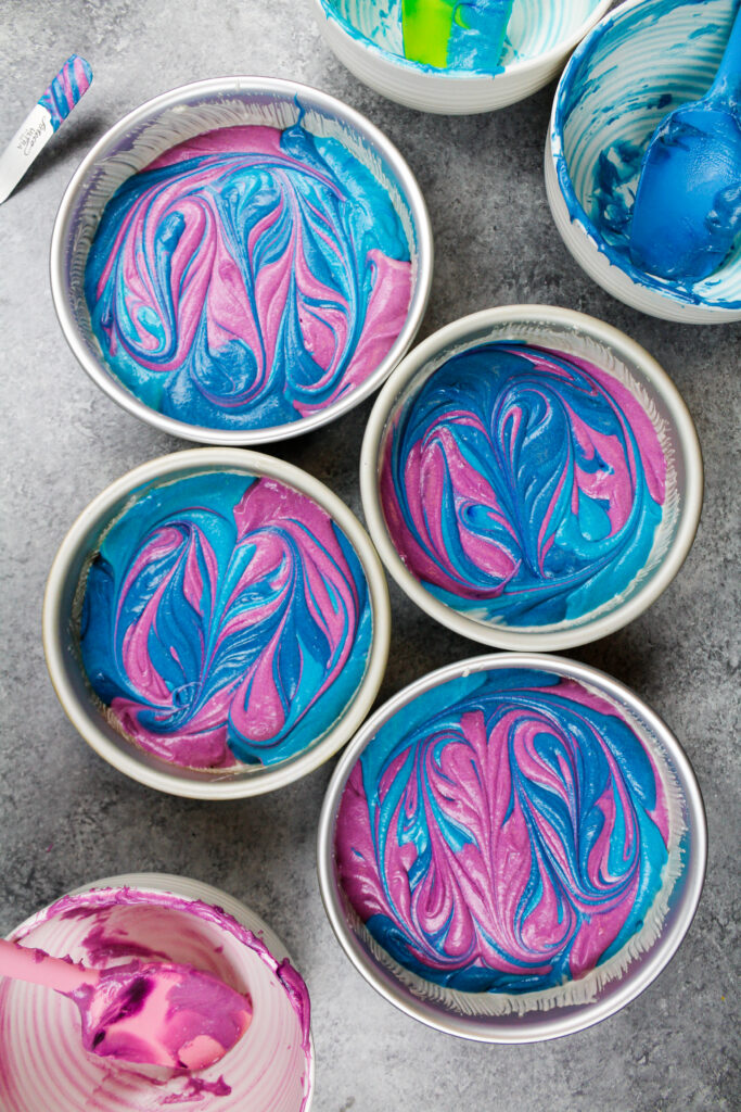 用紫色和蓝色的蛋糕糊做成的彩色漩涡蛋糕层图像