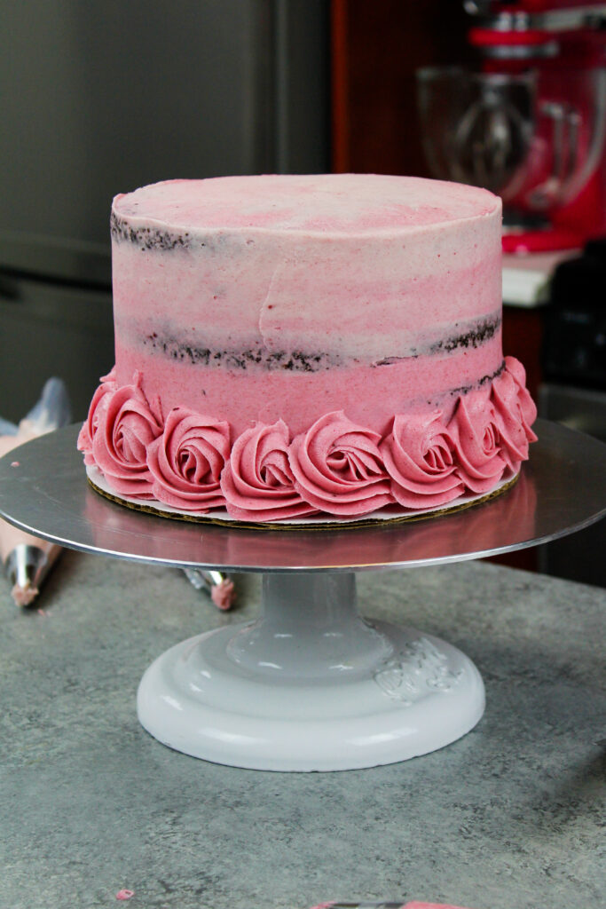 这是一张巧克力蛋糕的图片，上面撒了一层粉红色的糖霜，以搭配将被浇在上面装饰的奶油玫瑰结