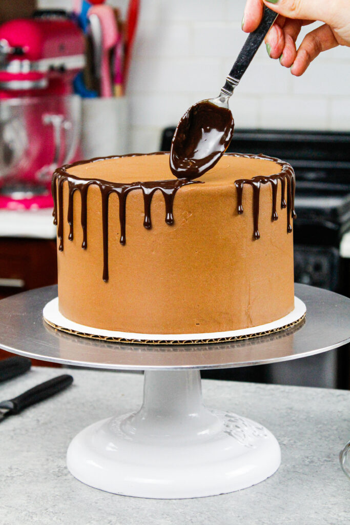 被添加到与匙子的巧克力滴蛋糕的巧克力ganache滴水的图象