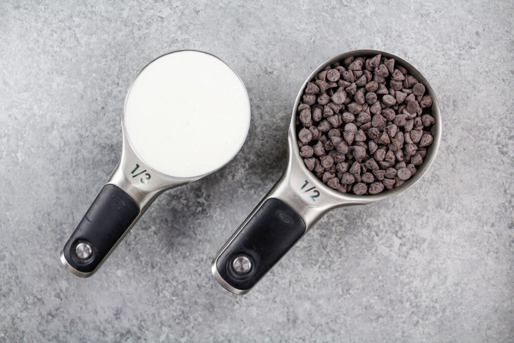 巧克力芯片和重的奶油的图象布置在柜台以制作巧克力蛋糕的巧克力ganache滴水