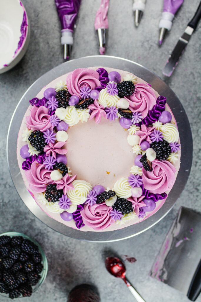 用紫色buttercream和新鲜的黑莓装饰的一个俏丽的黑莓层蛋糕的图象