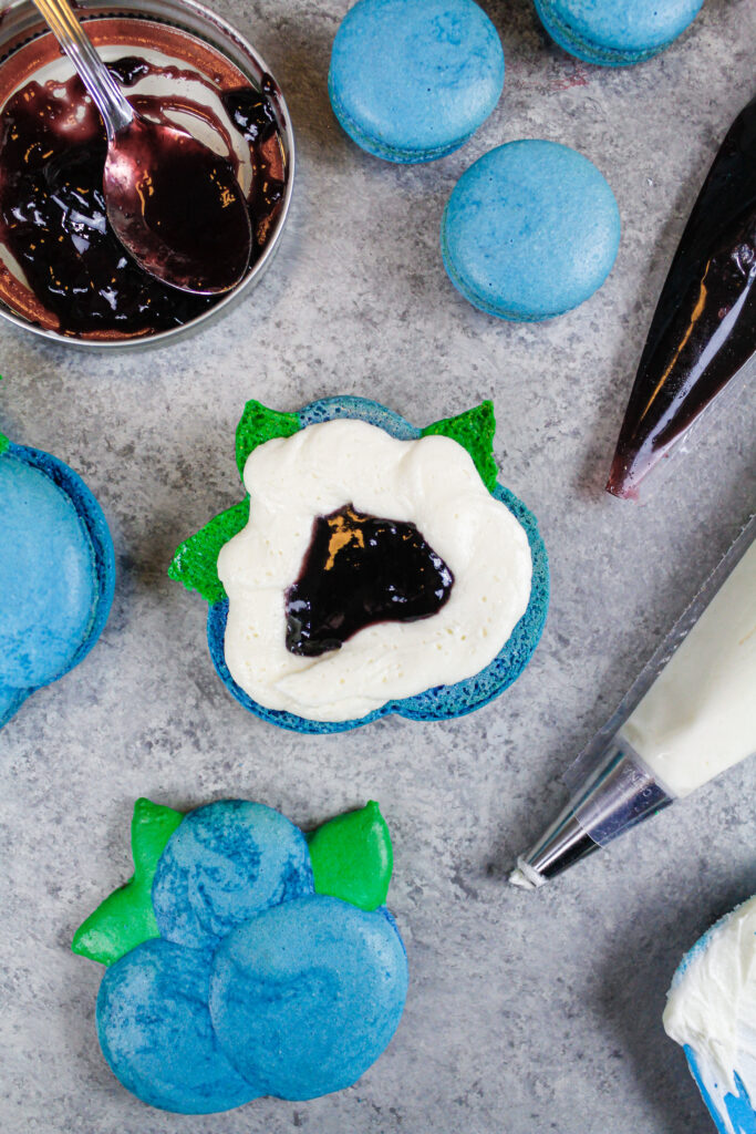 这是一个蓝莓马卡龙，里面填满了一圈美国奶油和蓝莓果酱