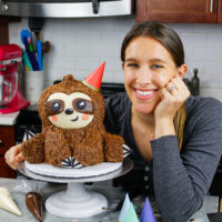 切尔斯·怀特的照片，这位烘焙博主和切尔斯维斯背后的内容创造者，手里拿着一个可爱的树懒生日蛋糕lpl外围赌注