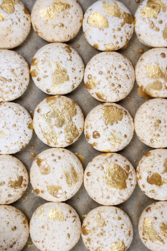 白色香草macaron贝壳的形象被溅起并用可食用的金油漆刷