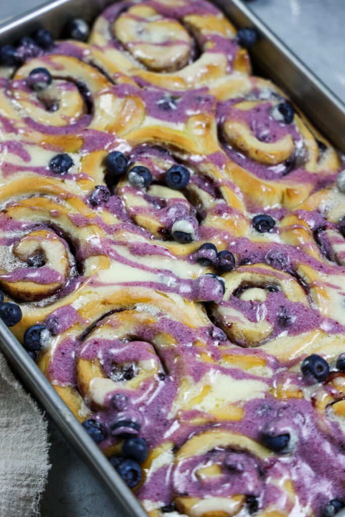 被烘烤和毛毛雨的蓝莓桂香卷的图象滴下香草和蓝莓釉