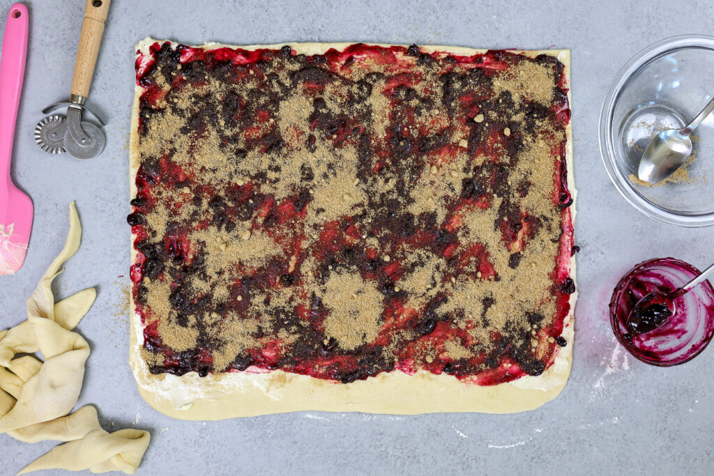 已充满肉桂红糖和蓝莓果酱的蓝莓桂香卷的图象并准备好卷起