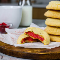 图片中的覆盆子芝士蛋糕饼干被咬了一口，以显示它们的覆盆子芝士蛋糕馅