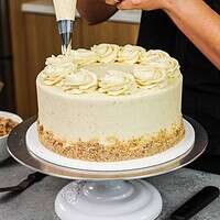 image of vanilla cake being frosted with brown butter buttercream frosting