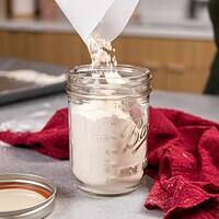 热处理面粉的图像被倒入梅森罐子中，以备将来使用