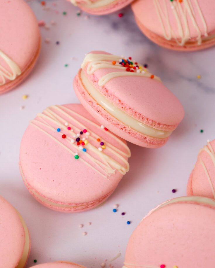 意大利马卡龙的图像，里面装满了白巧克力甘纳奇，上面放着白巧克力和洒