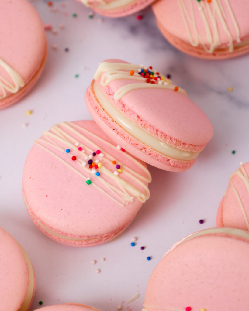 意大利马卡龙的图像，里面装满了白巧克力甘纳奇，上面放着白巧克力和洒