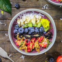 漂亮的花生酱阿卡伊碗的图像用新鲜水果，格兰诺拉麦片和一些食用花朵装饰