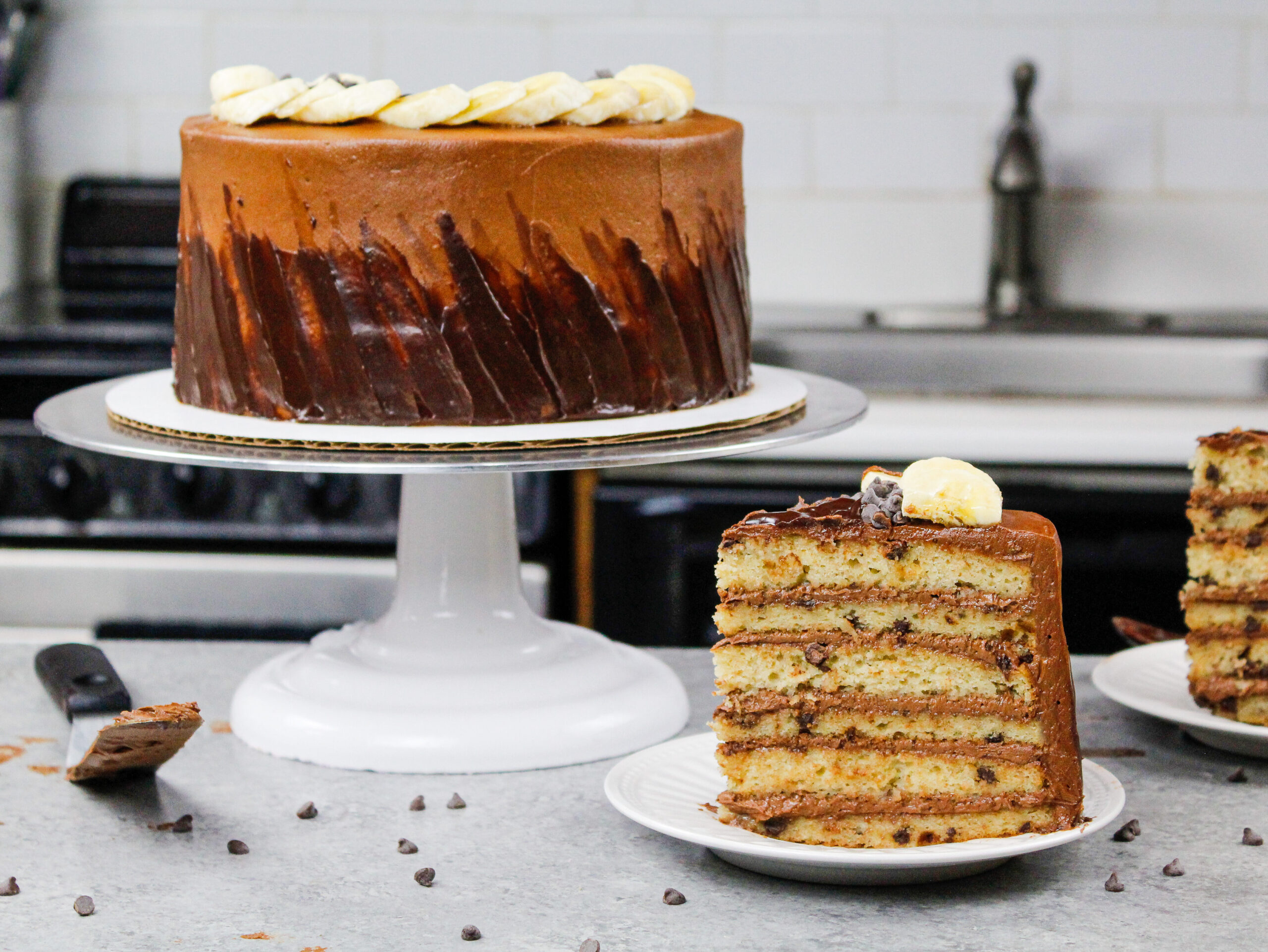 image of a slice of chocolate chip banana cake that's filled with delicious chocolate buttercream frosting