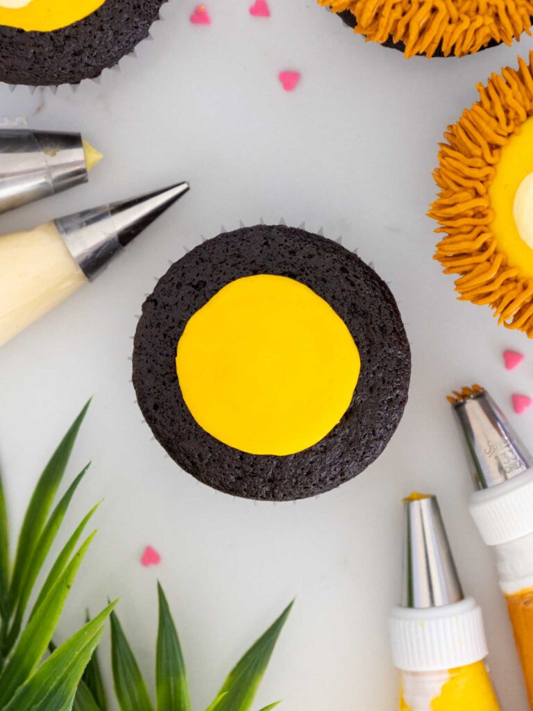 黄色奶油圆的图像，该圆圈已被管道并平滑至巧克力蛋糕上